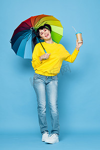 街头风格摄影照片_带着彩虹色雨伞摆出街头风格的快乐女人