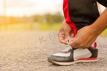 鞋子男孩摄影照片_男子在路边系鞋。或运动男子系鞋。