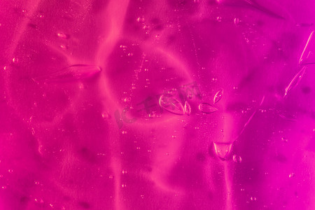 透明发光气泡摄影照片_橙色背景上带气泡和波浪的透明紫色凝胶的质地
