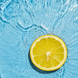 热带橙色夏季素食明亮多汁的柠檬在透明的夏季蓝色水中与波浪运动。