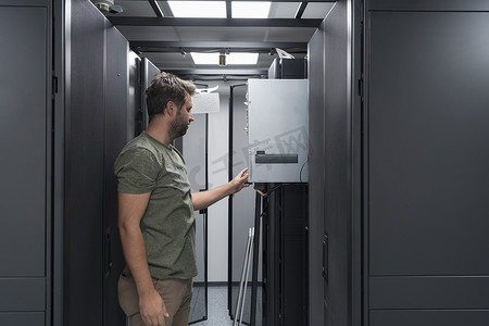 在服务器机房或数据中心工作的 IT 工程师技术人员将企业业务大型机超级计算机或加密货币采矿场的新服务器放入机架中。
