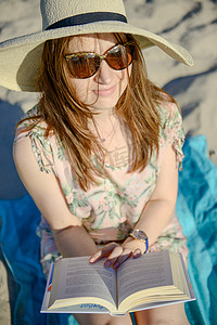 一个年轻的黑发女人在海滩上放松、读书的肖像