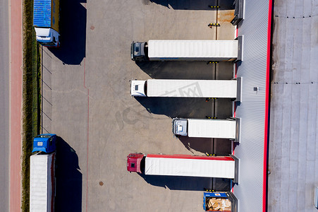 工业仓库装卸码头的空中侧面拍摄，许多卡车与半拖车装载/卸载商品