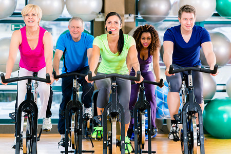 男女健身组在健身房旋转自行车