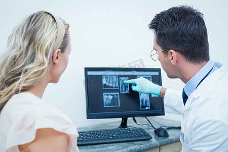 牙医在电脑上向妇女展示口腔 X 光检查
