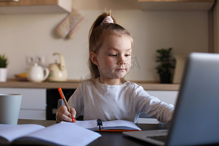手写快乐摄影照片_严肃的小女孩在家使用笔记本电脑在线学习手写，可爱快乐的小孩在 PC 上上互联网课程或课程。