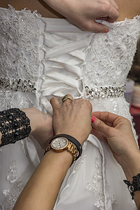伴娘为婚礼做准备，帮助新娘在仪式前系好婚纱。