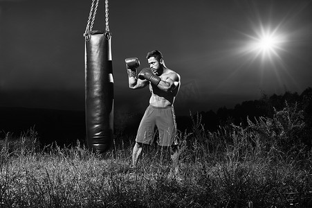 体育锻炼黑白摄影照片_一名男性拳击手用出气筒训练的单色照片
