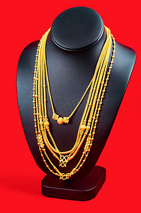 红色天鹅绒织物上带金项链的项链展示架