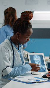 医生在平板电脑上进行 X 射线扫描以咨询患者