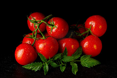 西红柿番茄摄影照片_黑桌上成熟的有机西红柿低调地滴着水