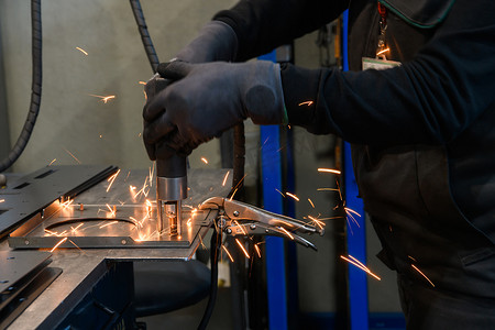 在现代金属生产和加工行业工作的一名妇女焊接产品并为数控机床做准备