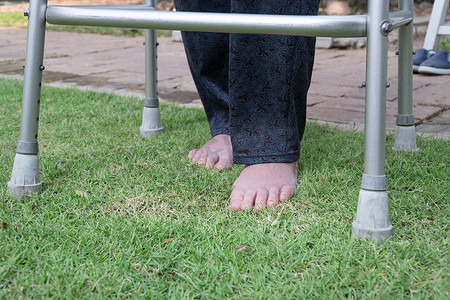 老妇赤脚在后院的草地上行走。