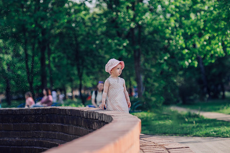 有小女儿的年轻母亲站在城市喷泉旁