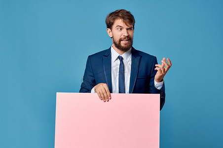 广告文案摄影照片_穿着西装的商务男士粉色空白样机广告文案空间蓝色背景