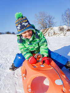 小男孩在冬季公园玩雪橇