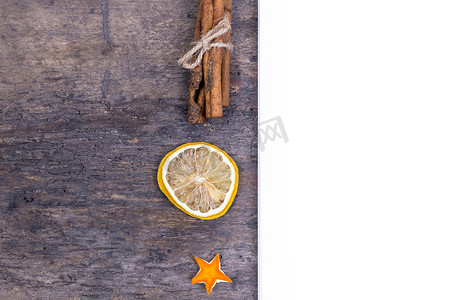 香橘摄影照片_一堆肉桂棒、干橙和橘子星放在旧木桌上，上面有白色的空纸。