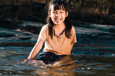 亚洲小女孩在森林溪流中玩耍。