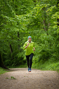 跑步运动的人摄影照片_森林里运动的年轻女跑步者。