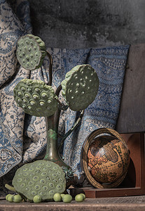 古董雕刻铁壶或花瓶中的新鲜绿色莲子荚，旧木椅上有木球。