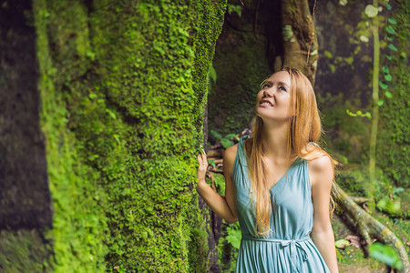 年轻女旅行者在长满青苔的巴厘岛花园里。