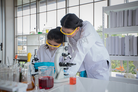 医学研究和科学家正在实验室中使用显微镜、平板电脑、试管、微量移液器和分析结果。