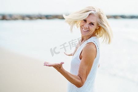 闲暇时光摄影照片_快乐的成熟女人在沙滩上散步，度过闲暇时光，享受闲暇时光