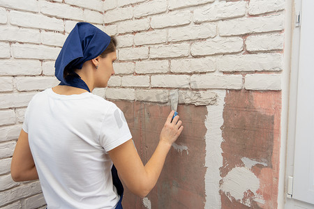 工程设计摄影照片_疲惫的女孩在墙上模仿砖砌工作