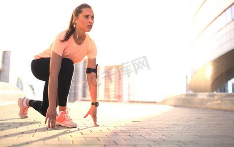 城市日落或日出时，年轻健身迷人的运动型女跑者在户外的起始位置