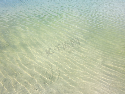 海滩上的浅波浪与半透明干净的沙子，呈绿黄色调。