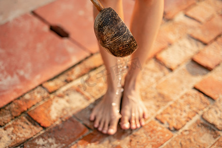 在海滩上用椰子壳制成的木勺从沙滩上洗脚。