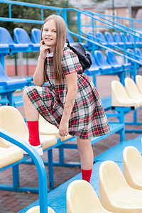 穿着校服的漂亮女孩在学校体育场的蓝色和黄色论坛上。