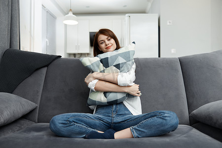 在家休息摄影照片_女人抱着枕头在沙发上舒适地在家休息