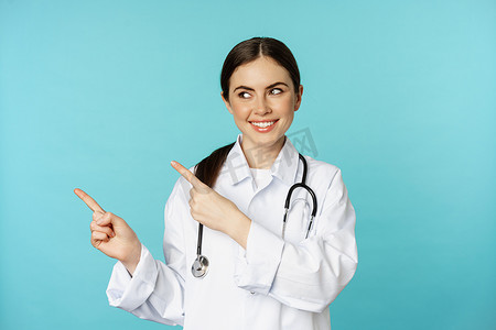 微笑的医务工作者的画像，穿白大衣的女医生拿着听诊器，手指向左，展示医疗诊所广告，绿松石背景