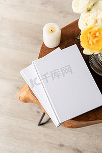 时尚木质咖啡桌上的白书空白封面模型，配有玫瑰花束、高角度视图