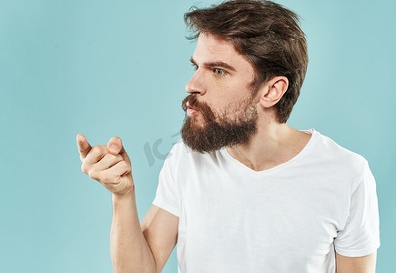 蓝色背景中身穿白色 T 恤深色头发的男人的裁剪视图令人困惑的侧视