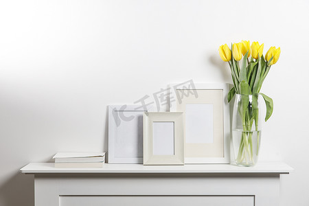 玻璃花瓶中的黄色郁金香和相框，白色抽屉柜上有铭文空间