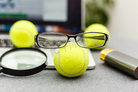 笔记本电脑、运动器材、网球、体育管理白桌上的眼镜的顶视图。商业理念。