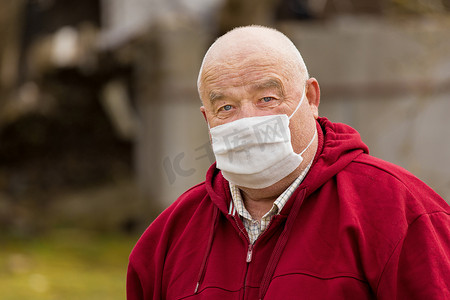 一位留着短发的欧洲老人的画像，戴着防护安全的医用口罩，特写