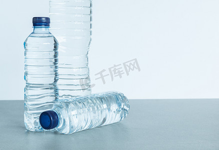 蓝色的矿泉水瓶子摄影照片_白色背景中三个装满矿泉水的塑料瓶