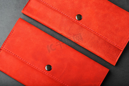 一对红色真皮钱包，深色背景顶视图上有铆钉。