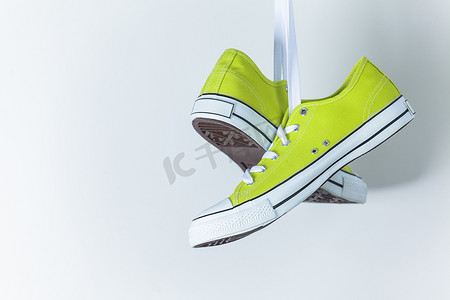 绿色的运动鞋摄影照片_墙上挂着一双新的绿色运动鞋
