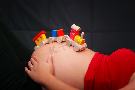 孩子们在怀孕肚子上的木制火车玩具。