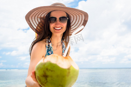 在热带海滩拿着新开椰子的女人