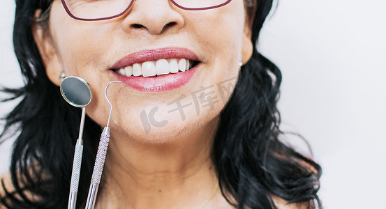 白色背景下完美微笑和牙医工具的特写、带牙医工具的女性完美微笑、完美微笑和牙医工具的概念