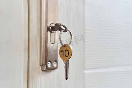 一把带有钥匙扣的钥匙，插在门的钥匙孔里。