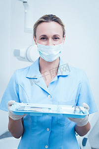戴着外科口罩的女牙医拿着工具托盘