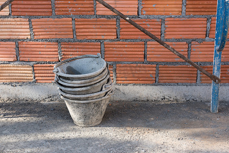 水泥桶摄影照片_施工时的水泥桶和红砖墙背景