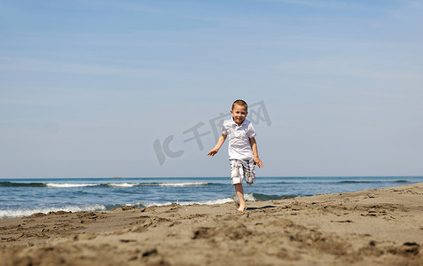 海滩奔跑的美摄影照片_在海滩上奔跑的小男孩