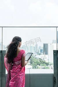 大风天，年轻的印度妇女在露台上使用平板电脑